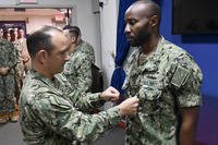 Command Master Chief Brian McDonough (left) promotes Culinary Specialist 2nd Class Matthew Ndambuki to petty officer first class during a meritorious advancement program (MAP) promotion ceremony at U.S. Naval Forces Central Command (NAVCENT), July 12, 2018. (U.S. Navy photo/Bryan Neal Blair)